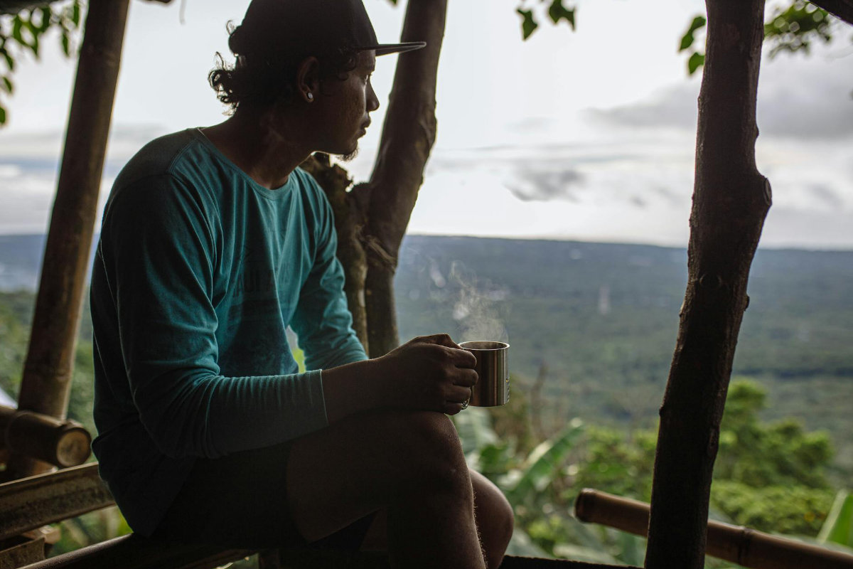Person contemplating regional landscape with coffee
